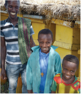Best.Gift.Ever in Action: Goshu Belete with two of his sons in front of some beehives