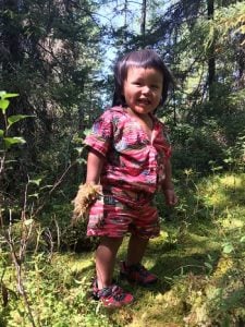 Best.Gift.Ever in Action: A toddler smiles with a handful of plants during a medicine picking trip.