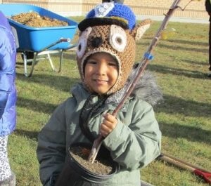 A young child holds a tree sapling 