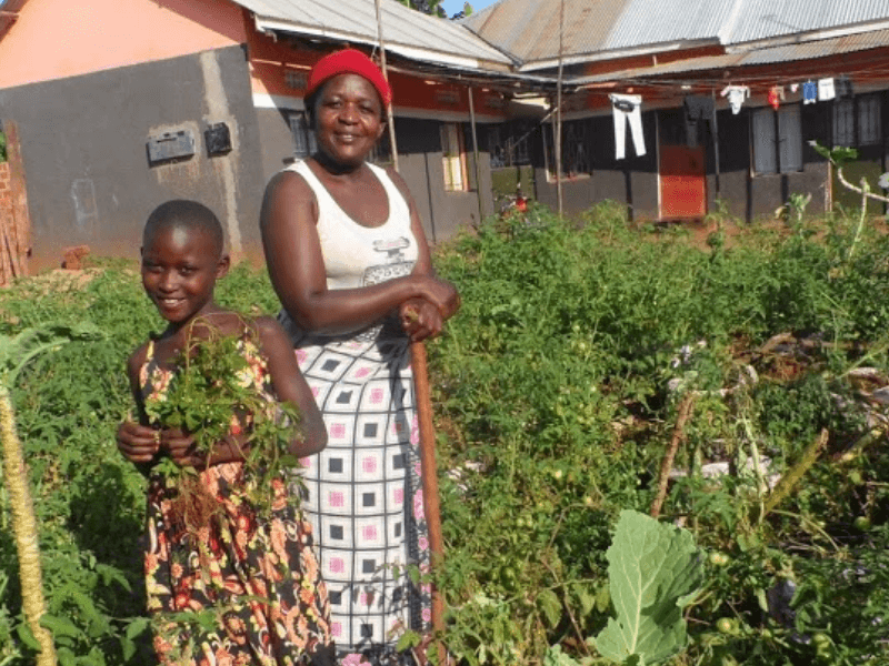 Mother and daugher smile in their garden holding produce