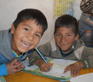 Two boys in Bolivia smiling while doing homework