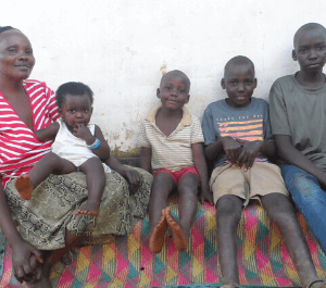 A woman holding her baby and seated with her 3 sons