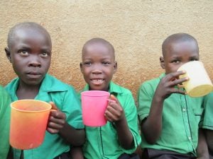 Three kids smiling as they eat lunch