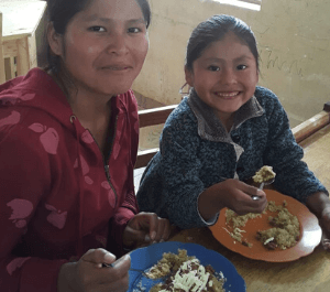A mother and her daughter smiling and sharing a meal together