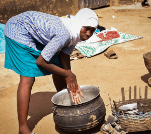 An adolescent girl mixes maize in a pot