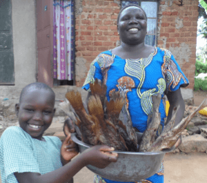 A little girl and her mother smile while holding a basket full of dried fish