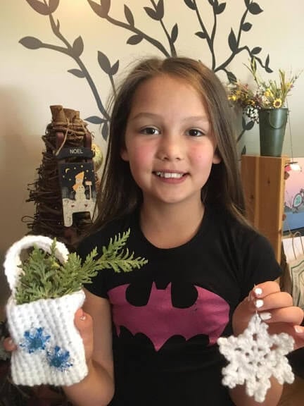 A young girl poses with homemade Christmas ornaments 