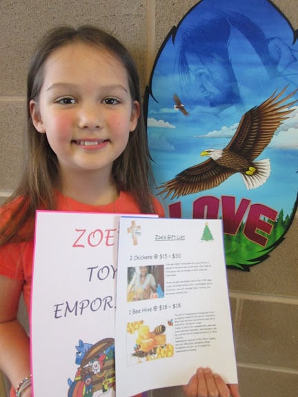 A girl smiles for the camera holding a catalogue she made