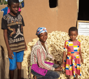 A women stands with her son and daughter and their haul of corn they grew