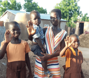 A women holding a baby with two younger kids smiling for the camera