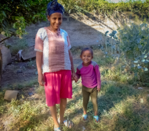A little girl holds the hand of her mom in their garden
