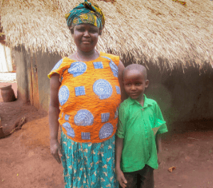 A mother and young son stand in front of their home embracing each other