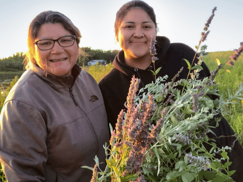 A mother and her daughter holding medicine plants