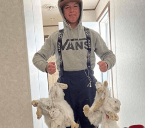 A young man holding rabbits he snared