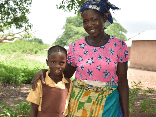 A mother gently puts her arm around her daughter as they smile for the camera