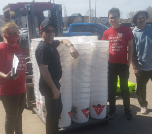 A group of people pose with stacks of plastic buckets