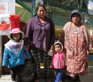 A woman, her mother and her two children stand with an emergency food hamper