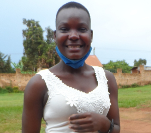 A teenage girl stands in a field, smiling for the camera