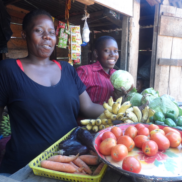 Women and her daughter stand in front of their vegetable produce