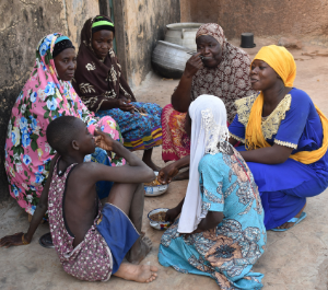 a family sits on the ground sharing a meal