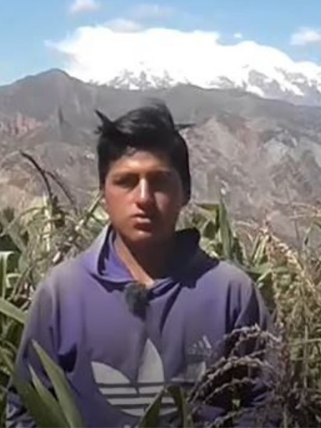 young man stands in field in front of moutain
