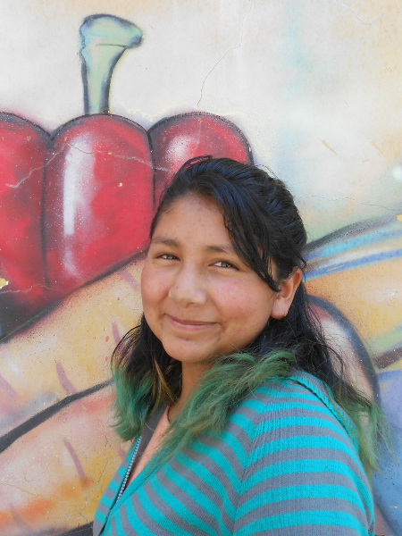 teenage girl stands in front of a mural of vegetables