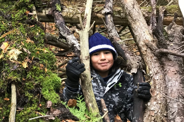 young boy sits among the trees