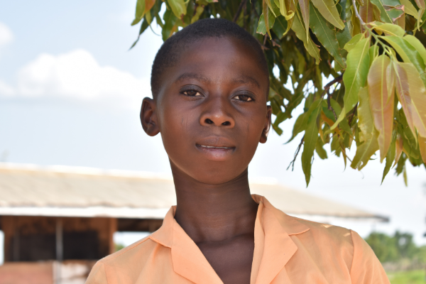 young girl standing in front of a tree 