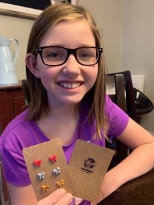Ella holds her hand made earrings