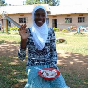 Vanessa with her lunch of posho and beans, out on the lawn of her school. 