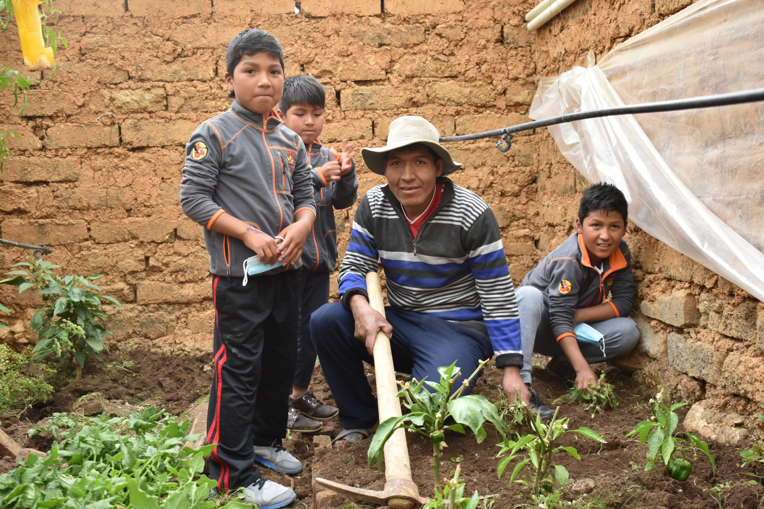 Francisco and his 3 sons smile while working in their family garden