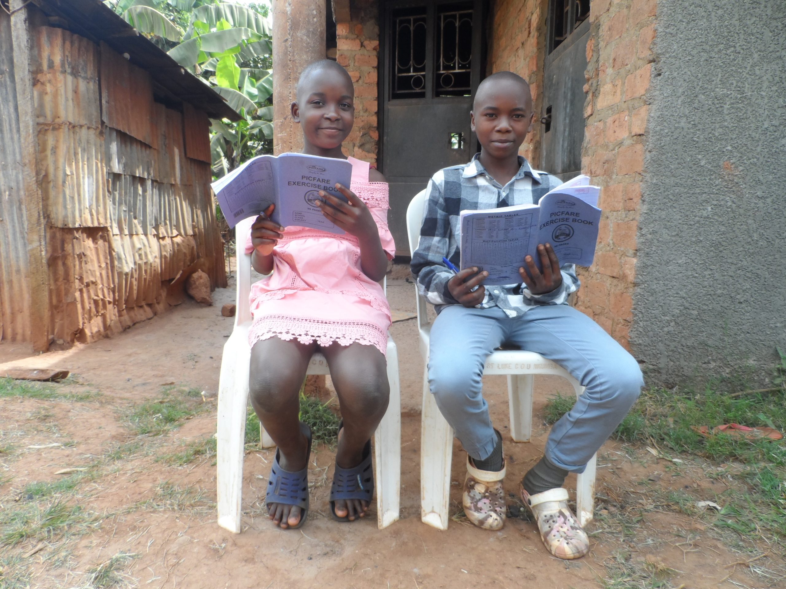 Nakato and Wasswa read in chairs in front of their home