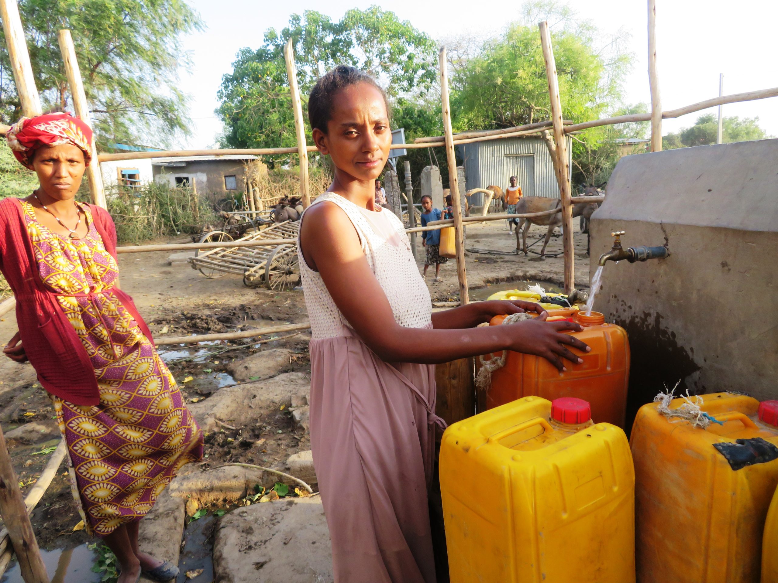a woman filling tanks of water from a local water tap
