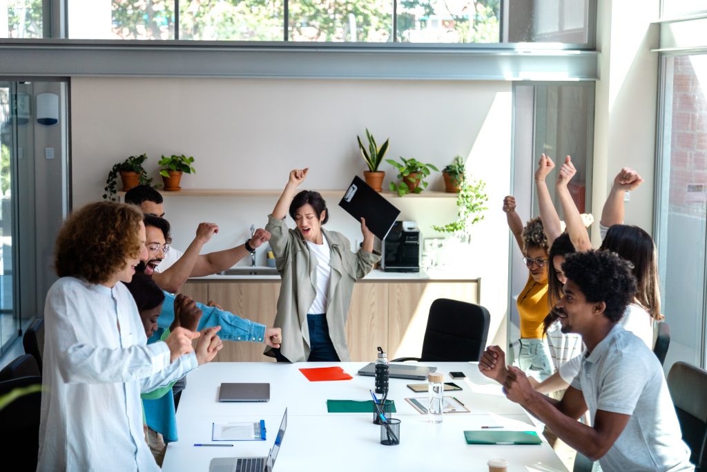 Multiracial coworkers and female boss dance in the office celebrating company results. Copy space. Business success concept.