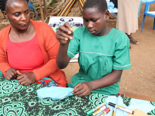 a teenage girl and a woman sew homemade menstrual pads