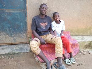 A father sits on a stoop with his arms around his daughter. they're both smiling brightly