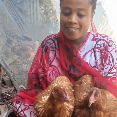 a woman smiles holding a chicken