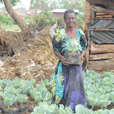 a woman stands in her garden holding a leafy crop in her hand
