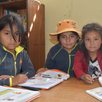 a group of children at a desk with classwork in front of them