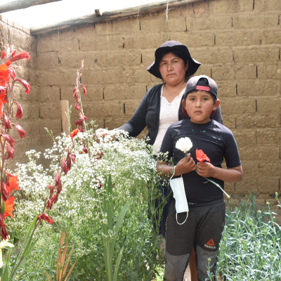 a mother and son stand in their flower garden together