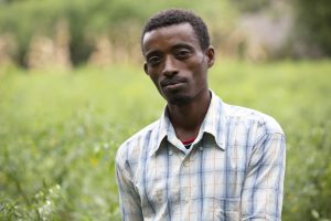 a headshot of a man standing in a green field