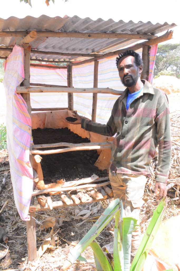 a man stands next to organic fertilizer harvested from manure