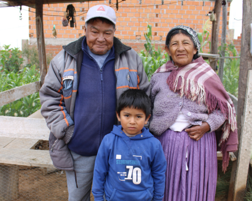 a young boy stands with his grandparents, smiling