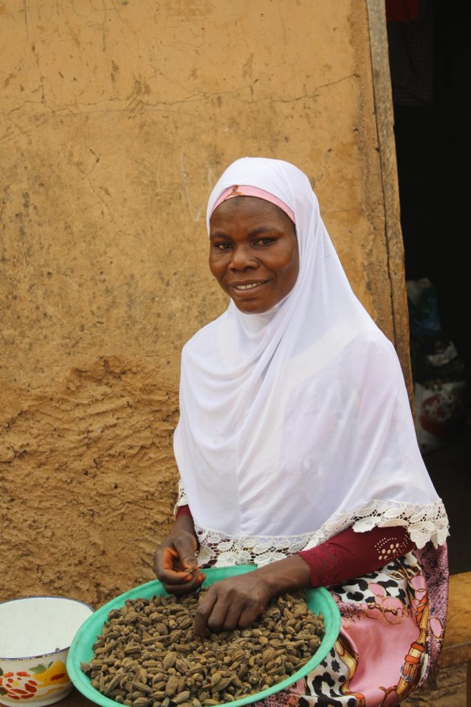 a woman sits in front of her home with harvested food