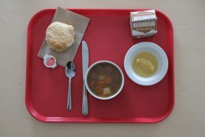 a school lunch comprised of soup, bun, and milk carton