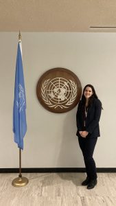 woman standing in front of UN logo and flag