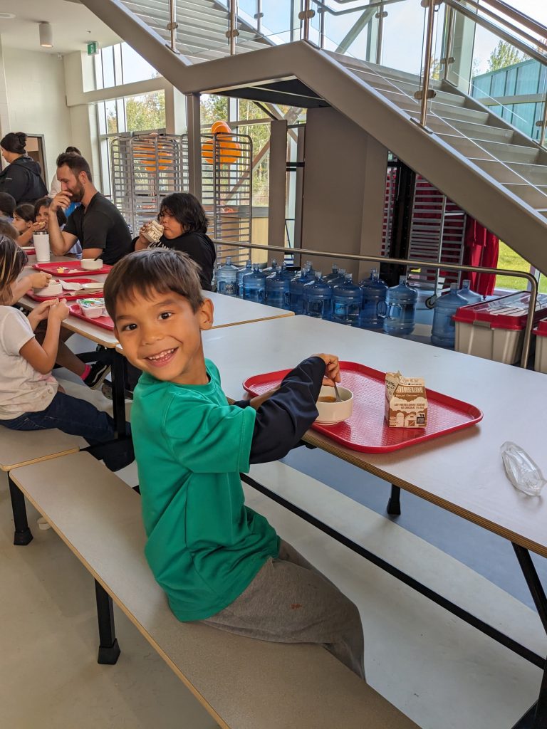 a little boy smiles while enjoying his lunch