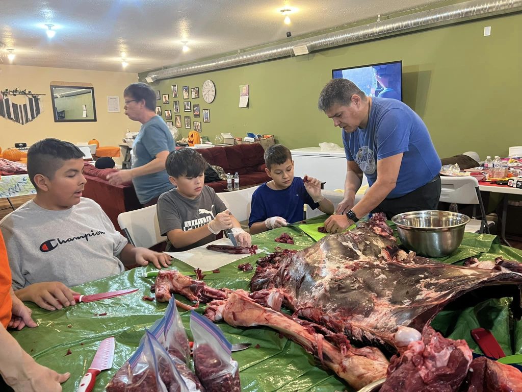 children holding butcher knives, carving up a moose carcass