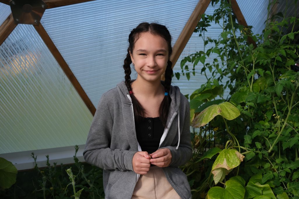 a girl stands in a greenhouse