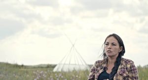 a woman talking with a tipi behind her